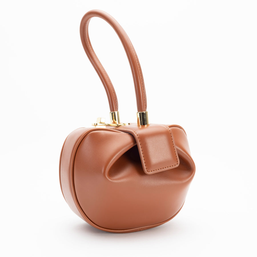 A brown, leather handbag with a solid pattern, featuring a top handle and a functional interior.