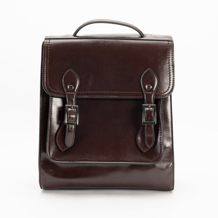A brown leather backpack with a structured silhouette, featuring a front flap with two buckles, a top handle and shoulder straps.